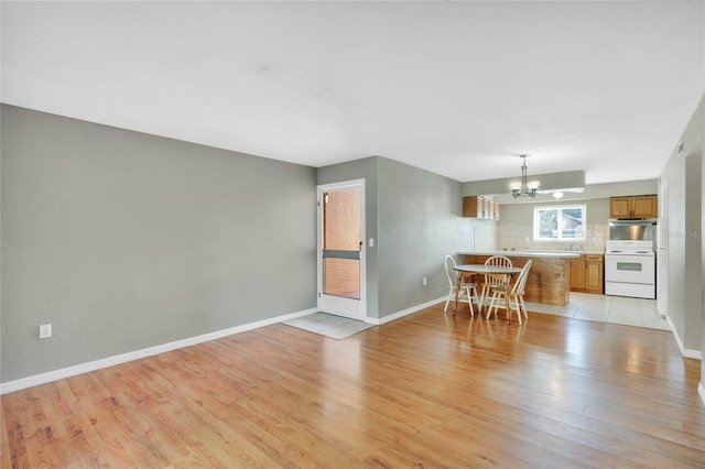 unfurnished dining area with an inviting chandelier and light wood-type flooring