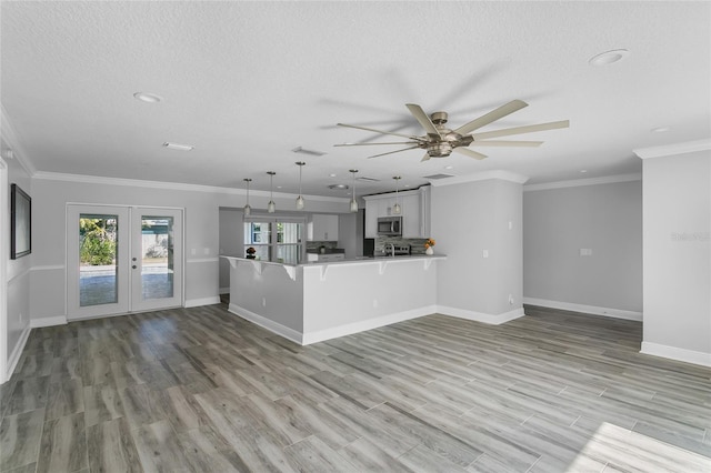 unfurnished living room featuring ceiling fan, french doors, light hardwood / wood-style flooring, and ornamental molding