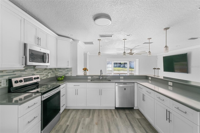 kitchen with white cabinets, sink, decorative light fixtures, kitchen peninsula, and stainless steel appliances