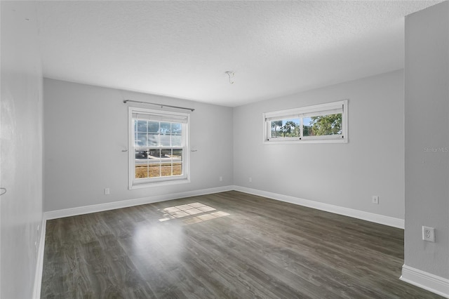 empty room featuring a textured ceiling, a healthy amount of sunlight, and dark hardwood / wood-style floors