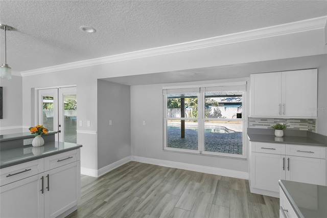 kitchen featuring tasteful backsplash, white cabinetry, crown molding, and decorative light fixtures