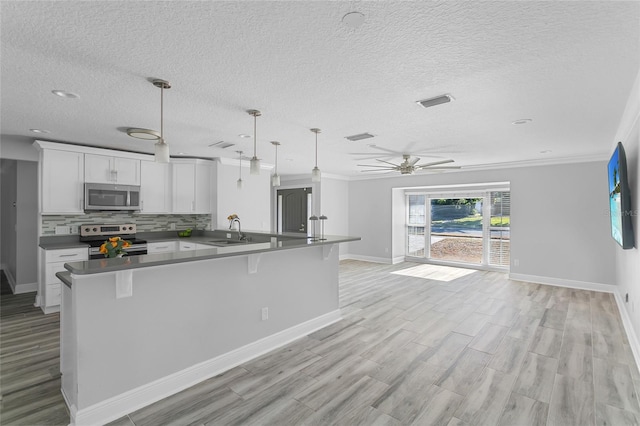 kitchen with backsplash, white cabinets, sink, appliances with stainless steel finishes, and decorative light fixtures