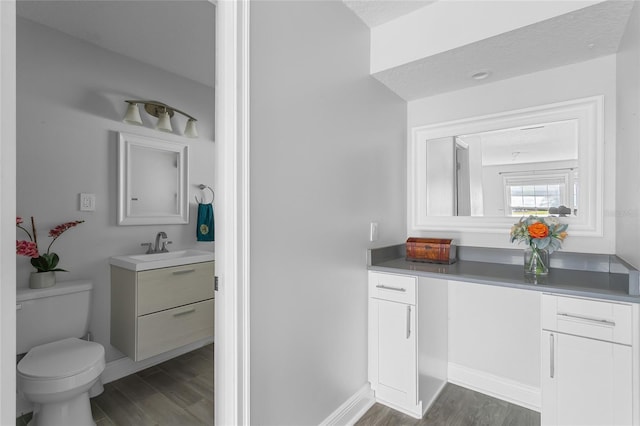 bathroom with hardwood / wood-style flooring, vanity, toilet, and a textured ceiling