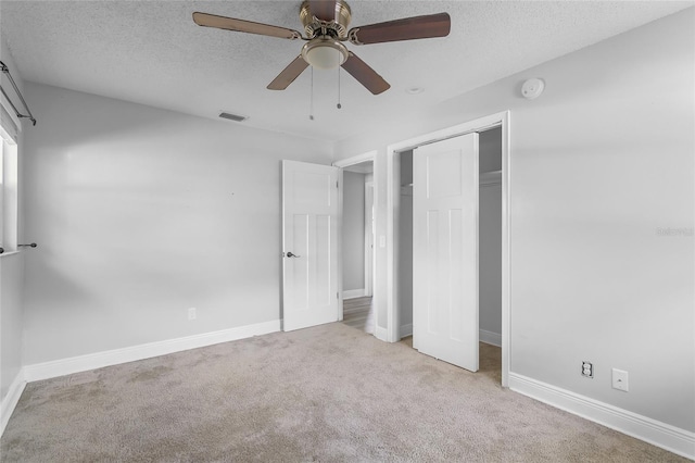 unfurnished bedroom with ceiling fan, light colored carpet, a textured ceiling, and a closet