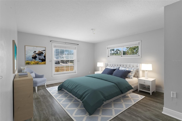 bedroom with a textured ceiling, multiple windows, and dark wood-type flooring