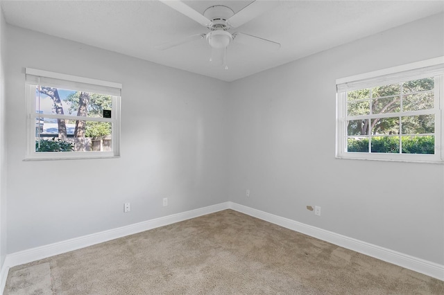 carpeted spare room featuring ceiling fan and a wealth of natural light