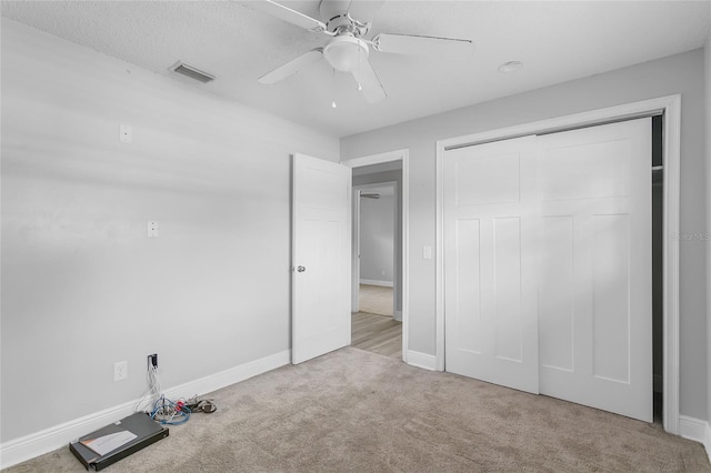 unfurnished bedroom with a closet, light colored carpet, and ceiling fan