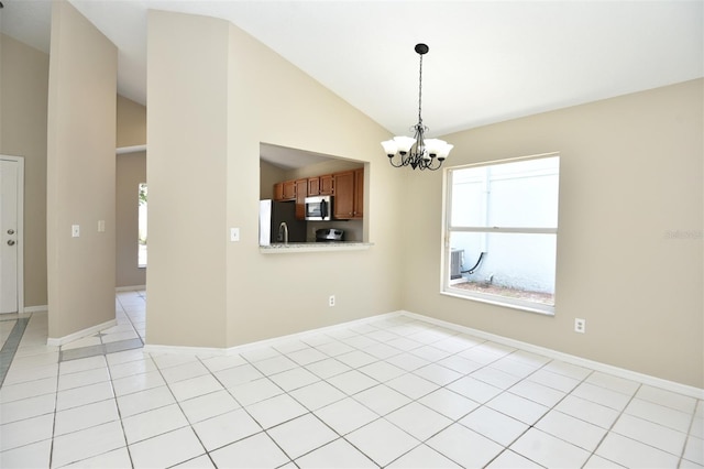 tiled spare room featuring an inviting chandelier and vaulted ceiling