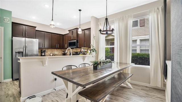 kitchen with light hardwood / wood-style floors, stainless steel appliances, a breakfast bar area, and pendant lighting