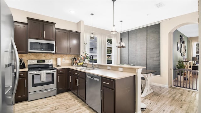 kitchen with plenty of natural light, stainless steel appliances, sink, and pendant lighting