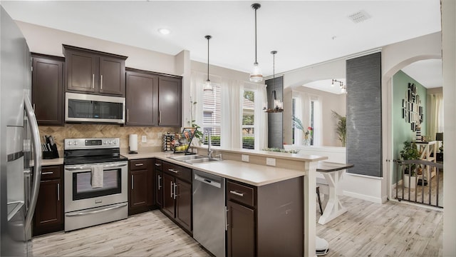 kitchen featuring hanging light fixtures, sink, dark brown cabinetry, appliances with stainless steel finishes, and light hardwood / wood-style floors