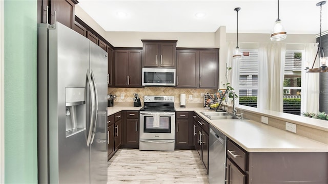 kitchen featuring sink, decorative light fixtures, stainless steel appliances, and dark brown cabinets