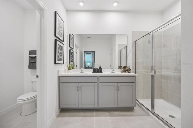 bathroom with vanity, toilet, tile patterned floors, and a shower with door