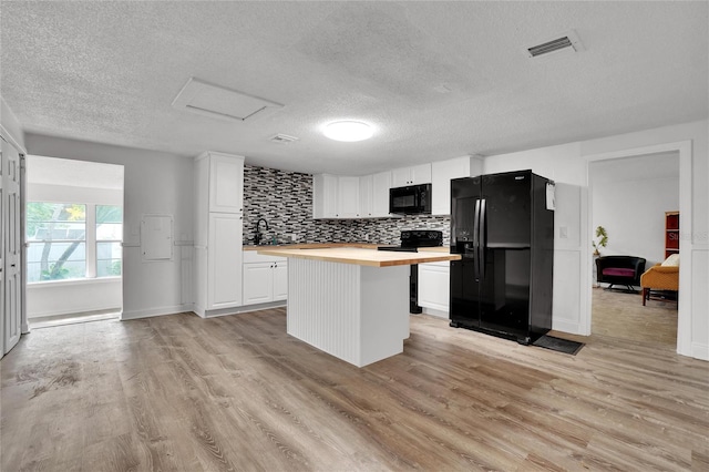 kitchen with white cabinetry, light hardwood / wood-style floors, a textured ceiling, a kitchen island, and black appliances