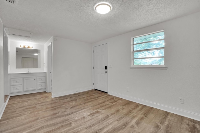 empty room with light hardwood / wood-style flooring, a textured ceiling, and sink