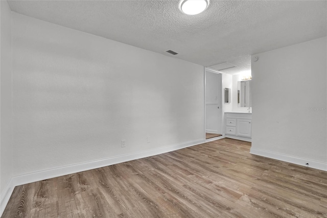 unfurnished room featuring light hardwood / wood-style floors and a textured ceiling