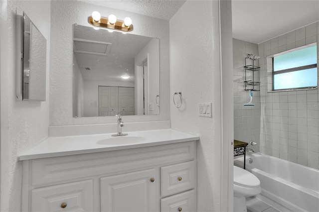 full bathroom with vanity, toilet, a textured ceiling, and tiled shower / bath