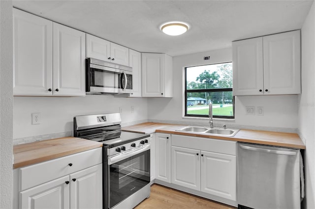 kitchen featuring butcher block counters, sink, white cabinets, and appliances with stainless steel finishes