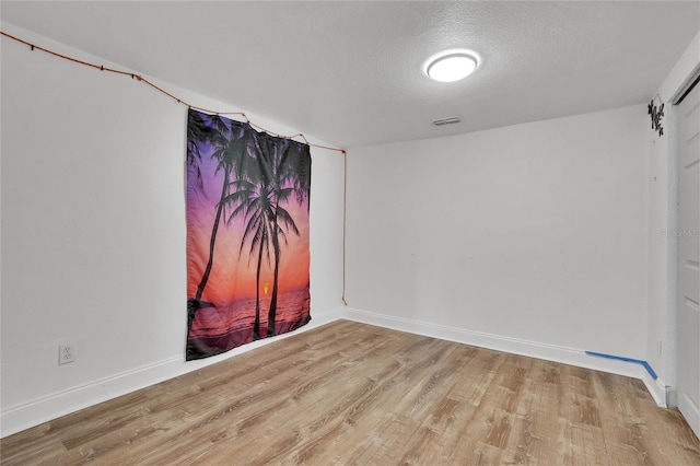 spare room with light hardwood / wood-style floors and a textured ceiling