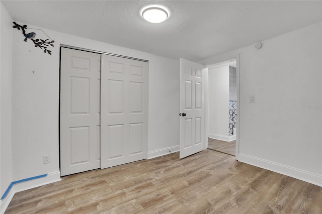 unfurnished bedroom featuring a closet, a textured ceiling, and light wood-type flooring