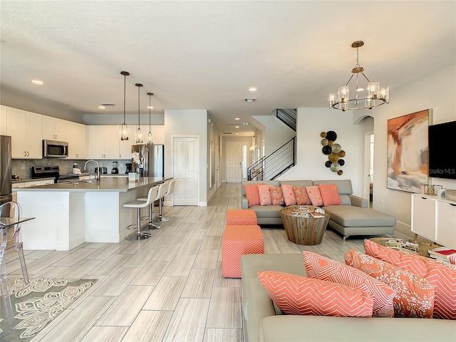 living room with a notable chandelier, light hardwood / wood-style floors, and sink