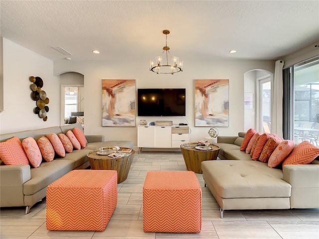 living room featuring a notable chandelier, a textured ceiling, and plenty of natural light