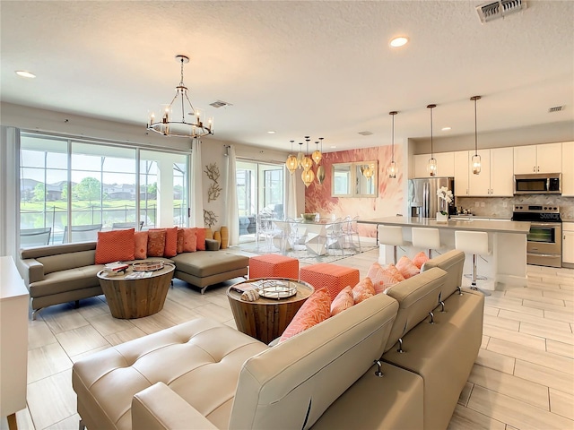 living room featuring a notable chandelier, a textured ceiling, and a healthy amount of sunlight