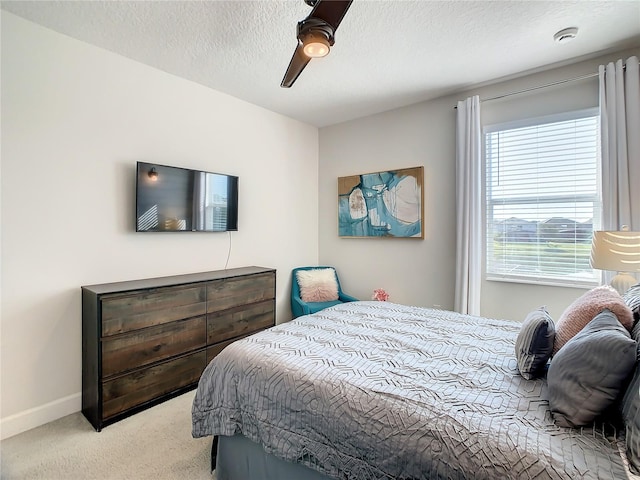 bedroom with light carpet, ceiling fan, and a textured ceiling