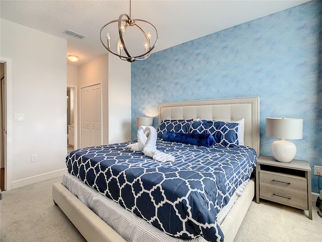 carpeted bedroom with an inviting chandelier, a closet, and a textured ceiling