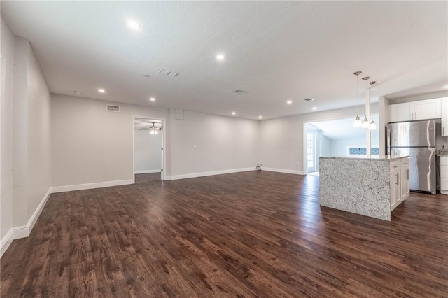 unfurnished living room with ceiling fan, a textured ceiling, and dark hardwood / wood-style flooring