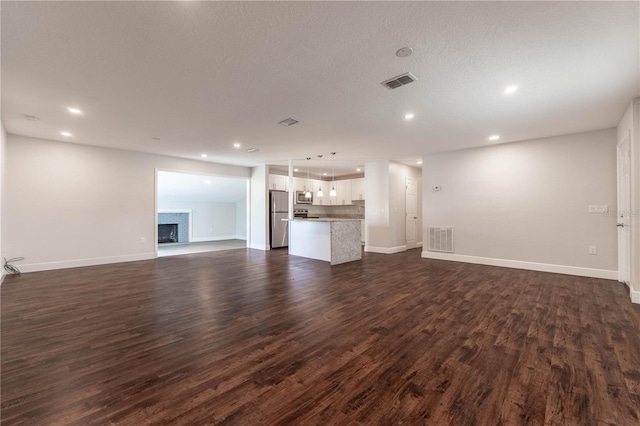 unfurnished living room with dark hardwood / wood-style floors and a textured ceiling