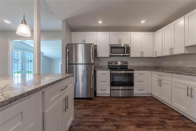 5709 Ridgeway Dr, Orlando, FL 32819 - kitchen featuring white cabinets, dark wood-style floors, light stone counters, decorative light fixtures, and appliances with stainless steel finishes