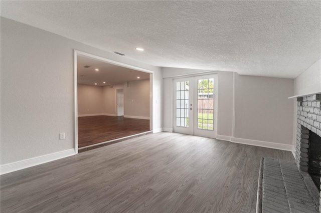 5709 Ridgeway Dr, Orlando, FL 32819 - unfurnished living room featuring wood finished floors, a textured ceiling, french doors, a brick fireplace, and visible vents