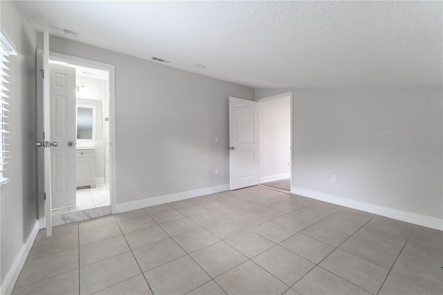 tiled spare room featuring a textured ceiling