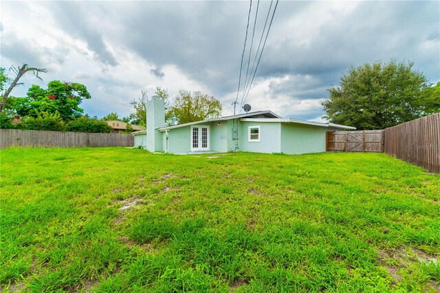 5709 Ridgeway Dr, Orlando, FL 32819 - back of property with a yard, french doors, a fenced backyard, and stucco siding