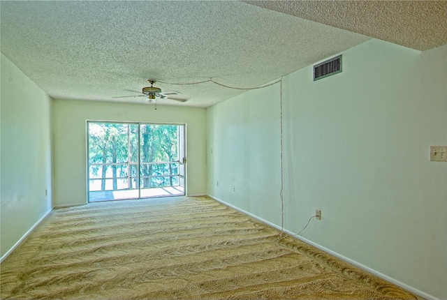 empty room featuring ceiling fan, light colored carpet, and a textured ceiling