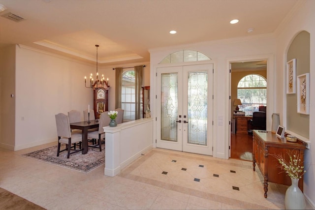 tiled entryway with crown molding, a chandelier, and french doors