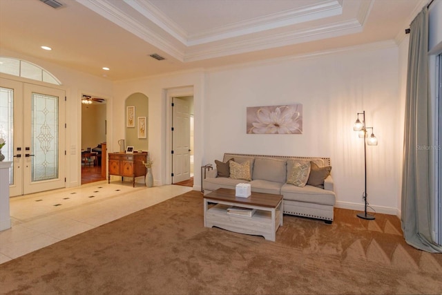 carpeted living room featuring a tray ceiling, french doors, and crown molding