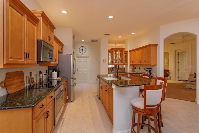 kitchen featuring light tile patterned floors, appliances with stainless steel finishes, sink, and dark stone counters