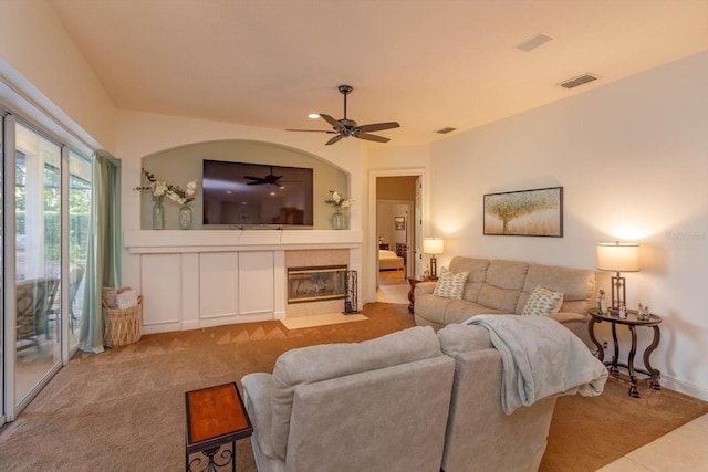 carpeted living room with ceiling fan and a tiled fireplace