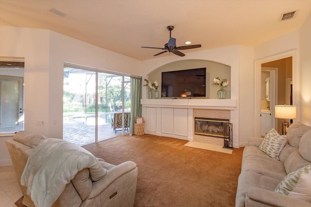 carpeted living room featuring a fireplace and ceiling fan