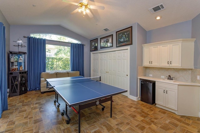 recreation room with a textured ceiling, lofted ceiling, ceiling fan, and sink