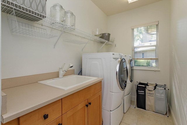 laundry area with light tile patterned floors, sink, independent washer and dryer, and cabinets