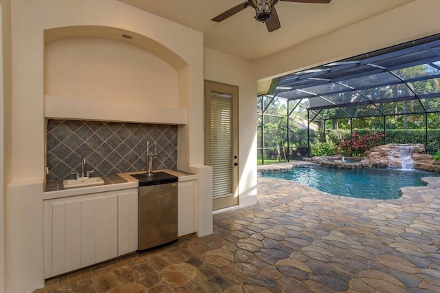 view of pool with sink, a patio, pool water feature, glass enclosure, and ceiling fan