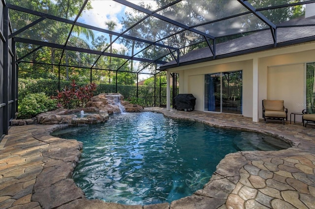 view of pool with area for grilling, glass enclosure, a patio, and pool water feature