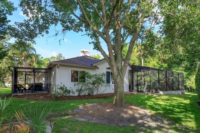 back of house featuring a lawn and a lanai