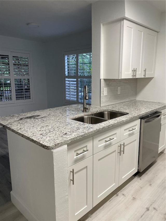 kitchen featuring sink, light stone countertops, light wood-type flooring, stainless steel dishwasher, and white cabinets