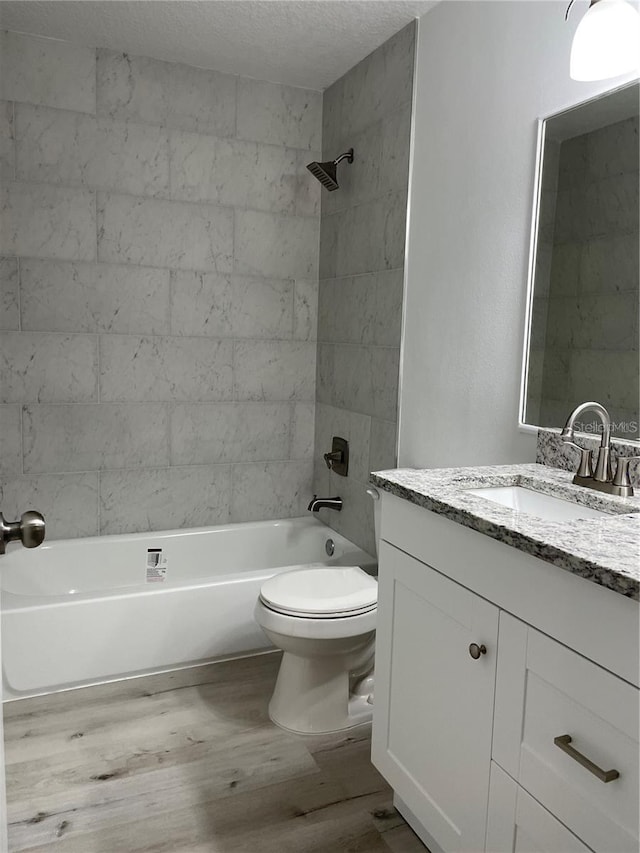 full bathroom featuring vanity, toilet, hardwood / wood-style floors, and tiled shower / bath