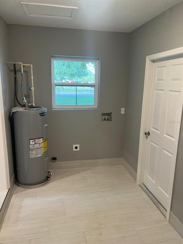 clothes washing area with electric dryer hookup, hookup for a washing machine, a textured ceiling, and electric water heater