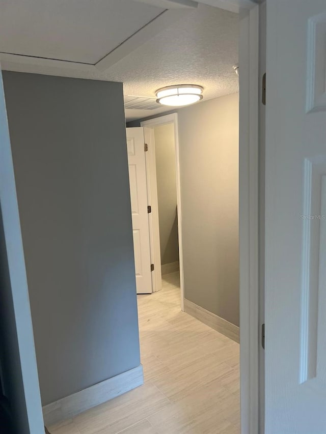 hallway featuring a textured ceiling and light hardwood / wood-style flooring